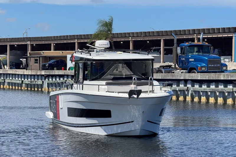 Slide: The Image of 2018 Jeanneau NC 895 boat on water near industrial area with truck in background. - 9