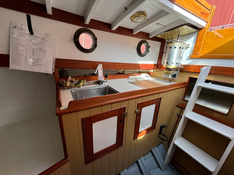 Slide: The Image of 1951 Custom Pilot Cutter galley with sink, portholes, and wooden cabinetry. - 12