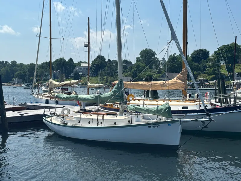 Slide: The Image of Vintage 1951 Custom Pilot Cutter sailboat docked in a scenic marina. - 2
