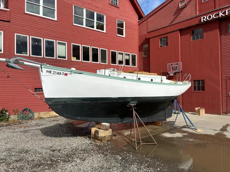 Slide: The Image of 1951 Custom Pilot Cutter on stands, red building background, Rockport sign visible. - 27