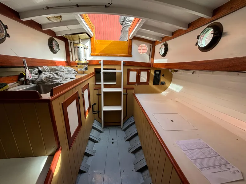 Slide: The Image of Interior of a 1951 Custom Pilot Cutter, featuring wooden cabinetry and nautical decor. - 37