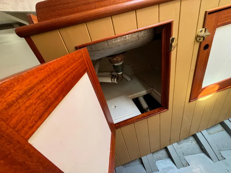 Slide: The Image of Open cabinet on 1951 Custom Pilot Cutter, revealing plumbing and storage space. - 38