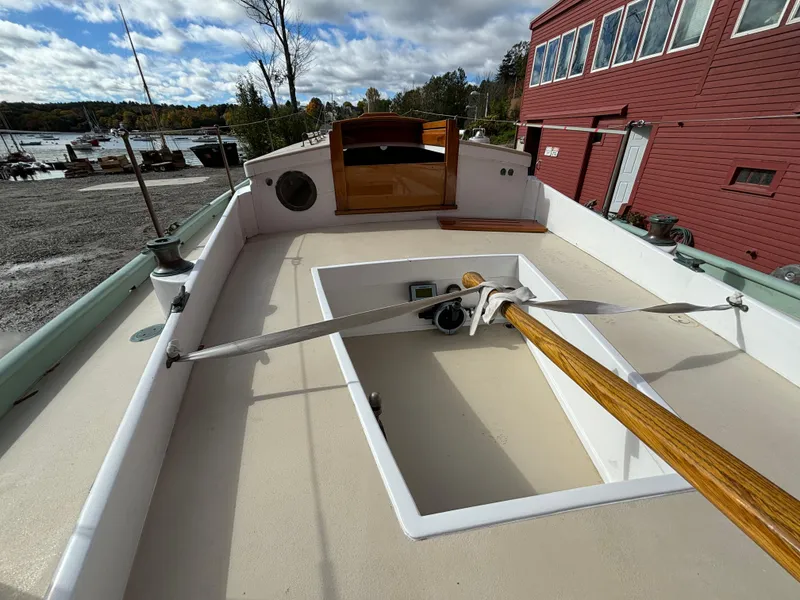 Slide: The Image of 1951 Custom Pilot Cutter deck with wooden oar, docked near red building. - 45