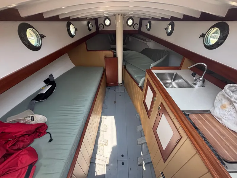 Slide: The Image of Interior of a 1951 Custom Pilot Cutter, featuring cozy bunks and a compact kitchenette. - 9