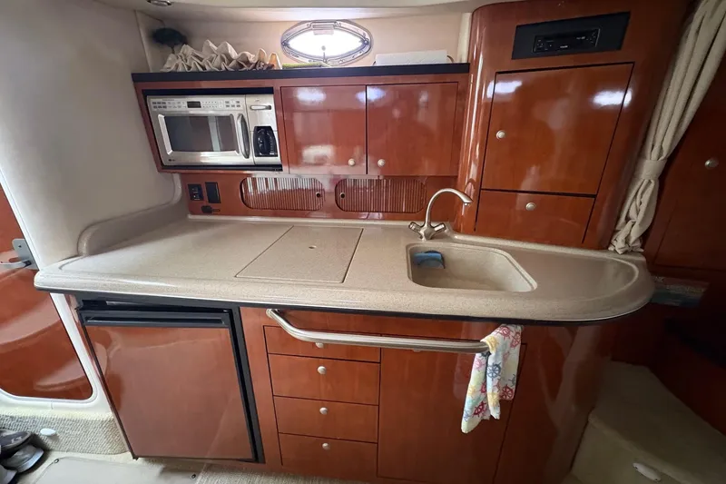 Slide: The Image of 2007 Sea Ray 340 Sundancer kitchen with microwave, sink, and wooden cabinetry. - 22