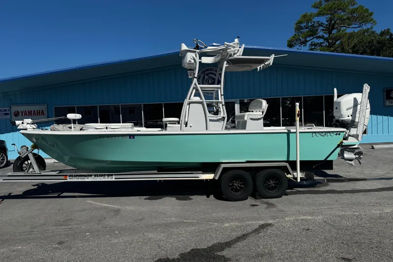 Slide: The Image of 2019 Dorado 25 Flat Deck boat on trailer, parked outside a blue building. - 0