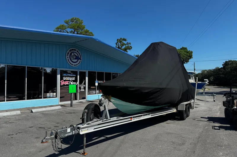 Slide: The Image of 2019 Dorado 25 Flat Deck boat covered on trailer outside a blue building. - 34