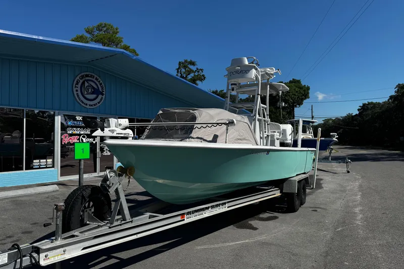 Slide: The Image of 2019 Dorado 25 Flat Deck boat on trailer outside marina under clear blue sky. - 8