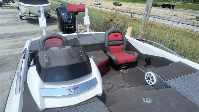 Slide: The Image of 2021 Vexus VX20 boat interior with red and black seating, parked outdoors. - 11