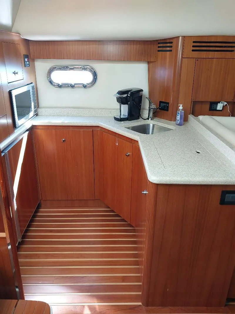 Slide: The Image of 2003 Tiara Yachts 4400 Sovran galley with wood cabinetry, countertop, sink, and appliances. - 11