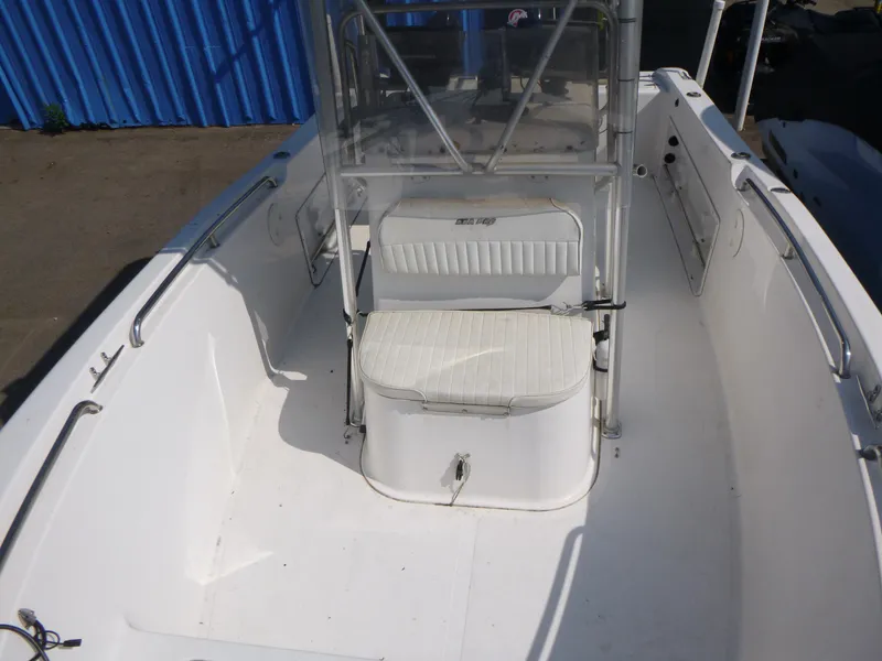 Slide: The Image of 2003 Sea Pro 220 Center Console boat interior with seating and console, docked near blue structure. - 6