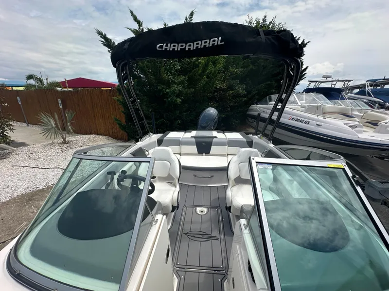 Slide: The Image of 2023 Chaparral 21 SSi OB boat with open deck and canopy, parked outdoors. - 20