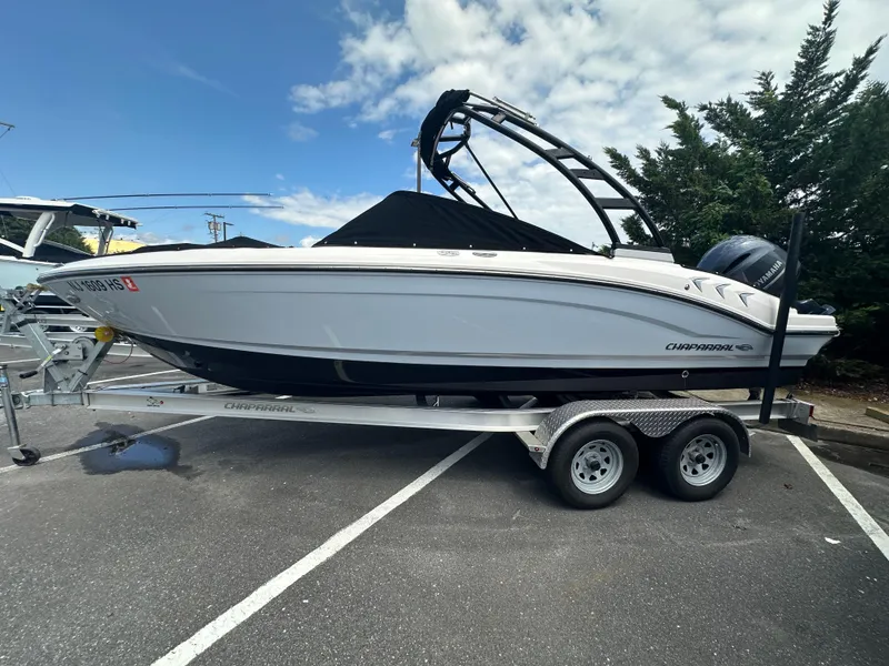 Slide: The Image of 2023 Chaparral 21 SSi OB boat on trailer, parked outdoors under cloudy sky. - 25