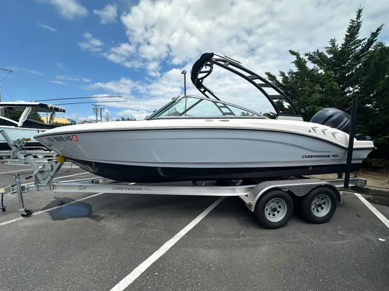 Slide: The Image of 2023 Chaparral 21 SSi OB boat on trailer, parked outdoors under a cloudy sky. - 3