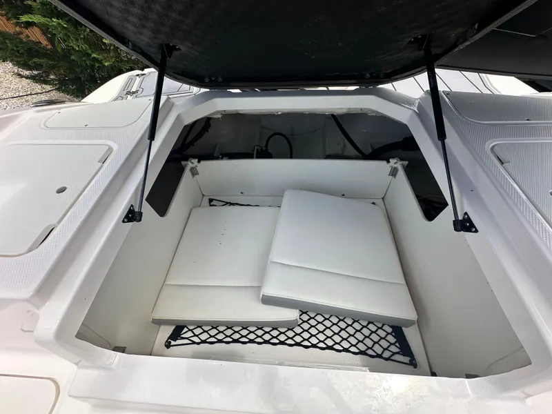 Slide: The Image of Open storage compartment in 2023 Chaparral 21 SSi OB boat, featuring white cushions and netting. - 8