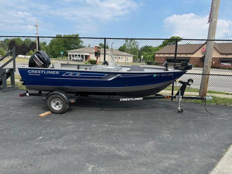 Slide: The Image of 2017 Crestliner 1600 Vision boat on trailer, parked outdoors near a fence. - 1