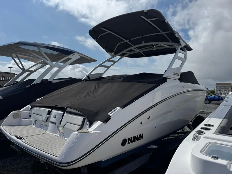Slide: The Image of 2023 Yamaha Boats 252SD with black cover, parked outdoors under cloudy sky. - 23