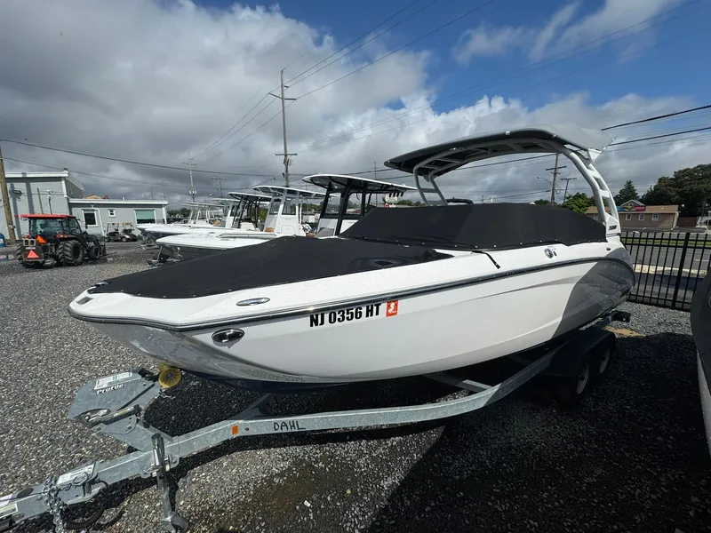 Slide: The Image of 2023 Yamaha Boats 252SD on trailer, covered, parked outdoors under cloudy sky. - 24