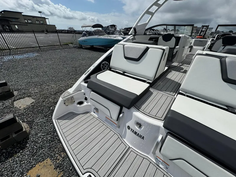 Slide: The Image of 2023 Yamaha Boats 252SD with sleek seating and modern design in a marina setting. - 8