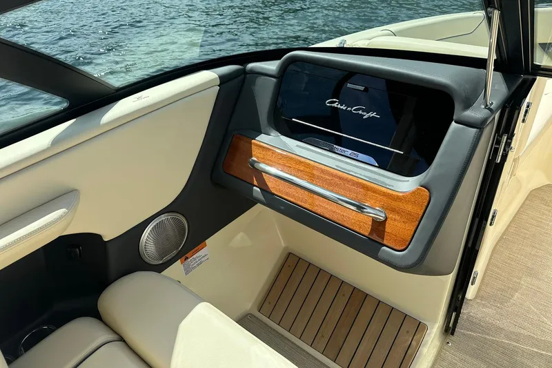 Slide: The Image of 2026 Chris-Craft Sportster 25 interior with wood accents and speaker, near water. - 11