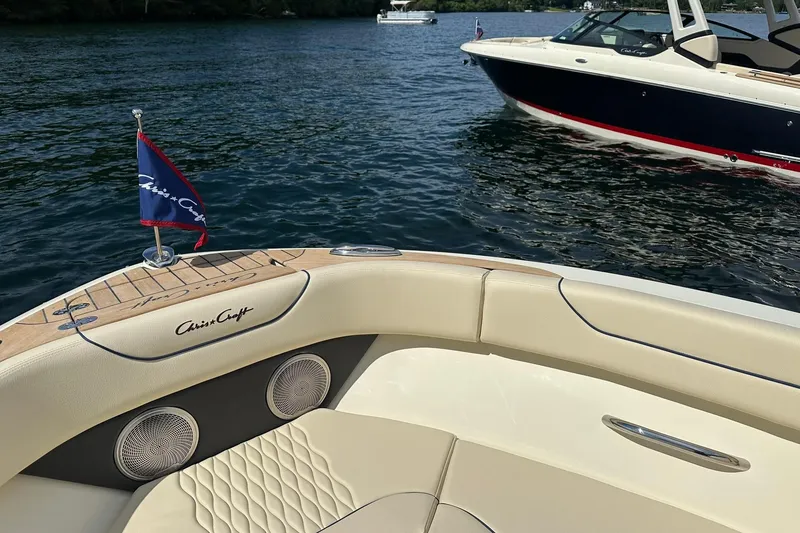 Slide: The Image of 2026 Chris-Craft Sportster 25 boat on water, featuring elegant seating and branded flag. - 15