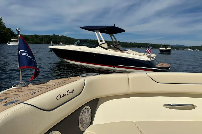 Slide: The Image of 2026 Chris-Craft Sportster 25 boat on a lake, featuring elegant design and American flag. - 16