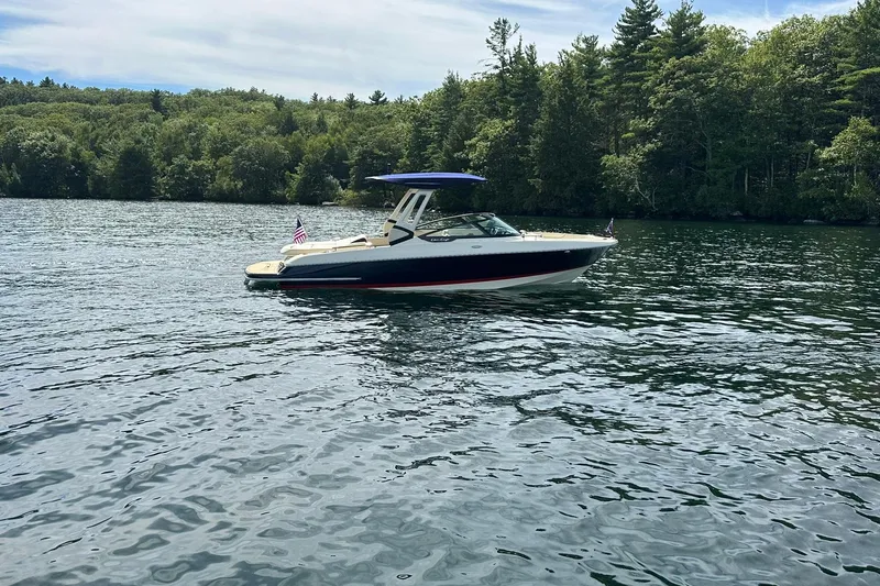 Slide: The Image of 2026 Chris-Craft Sportster 25 boat on a serene lake with forested background. - 3