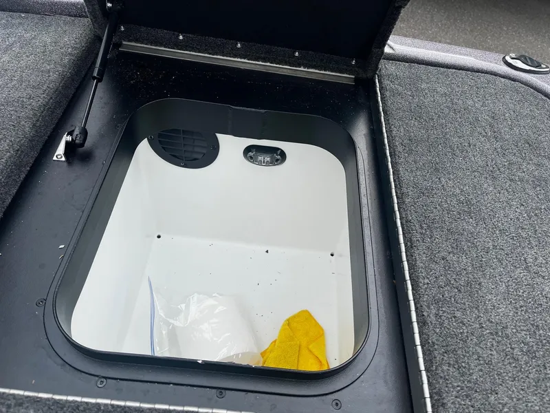 Slide: The Image of Open storage compartment in 2024 Skeeter ZXR 20 boat, featuring carpeted interior and yellow cloth. - 11
