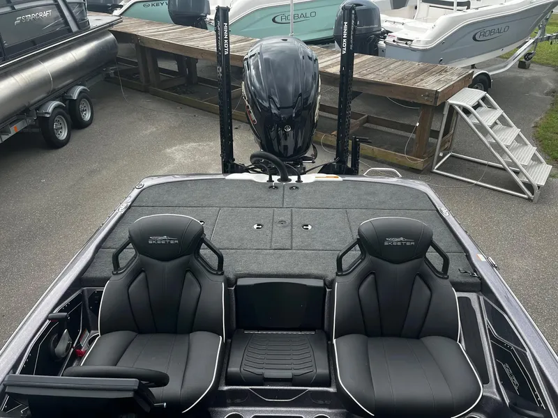 Slide: The Image of 2024 Skeeter ZXR 20 boat interior with dual seats and motor, parked among other boats. - 15