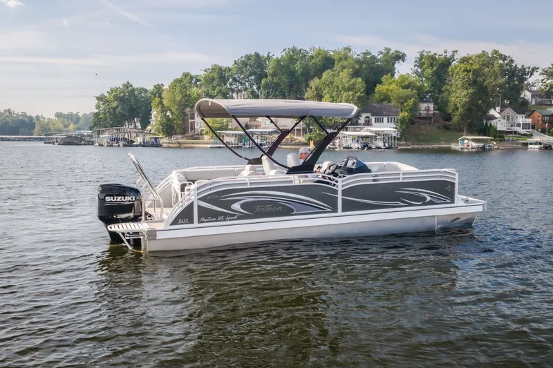Slide: The Image of 2025 JC Neptoon 25TT Sport pontoon boat on a scenic lake with lush greenery. - 55