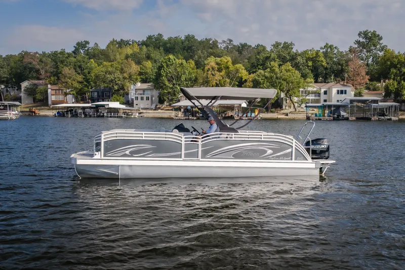The Image of 2025 JC Neptoon 25TT Sport pontoon boat on a scenic lake with houses in the background. - 3