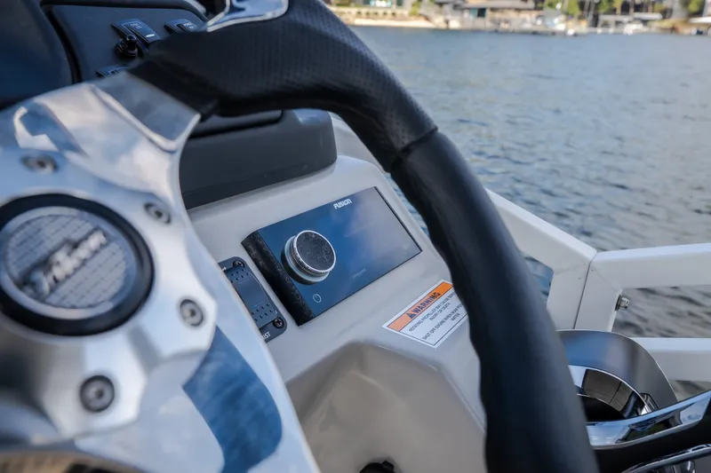 Slide: The Image of Steering wheel and dashboard of 2025 JC Neptoon 25TT Sport boat on water. - 11