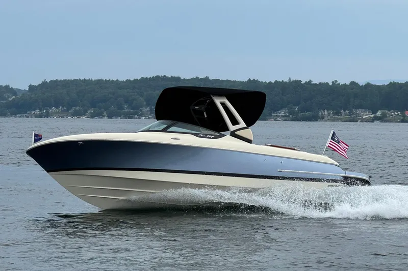 The Image of 2026 Chris-Craft Sportster 25 cruising on a lake with American flag. - 0