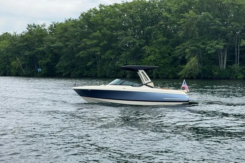 Slide: The Image of 2026 Chris-Craft Sportster 25 boat cruising on a serene lake with lush green trees. - 4