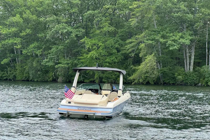 Slide: The Image of 2026 Chris-Craft Sportster 25 boat cruising on a serene lake with lush green trees. - 8