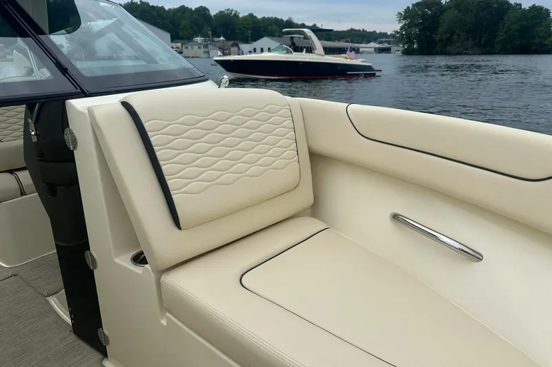 Slide: The Image of 2026 Chris-Craft Sportster 25 boat interior with beige seating, on a scenic lake. - 26