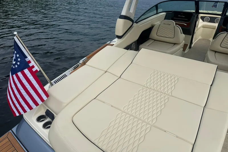 Slide: The Image of 2026 Chris-Craft Sportster 25 boat with elegant seating and American flag on calm water. - 14