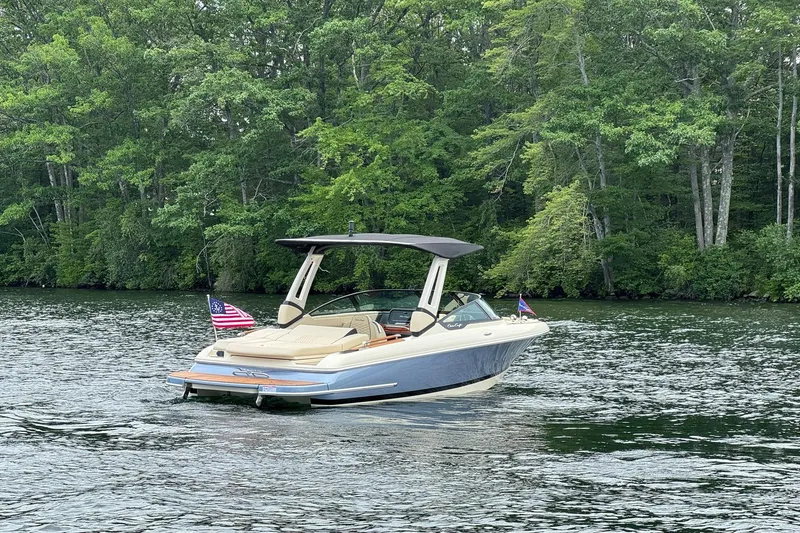 Slide: The Image of 2026 Chris-Craft Sportster 25 boat on a serene lake, surrounded by lush greenery. - 9