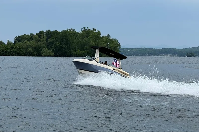 Slide: The Image of 2026 Chris-Craft Sportster 25 cruising on a lake with an American flag. - 2