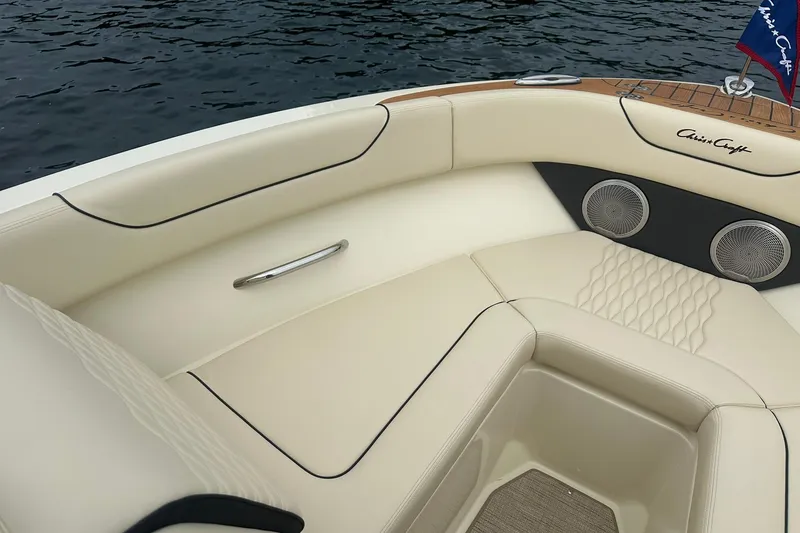 Slide: The Image of 2026 Chris-Craft Sportster 25 boat interior with elegant seating and speakers by the water. - 23