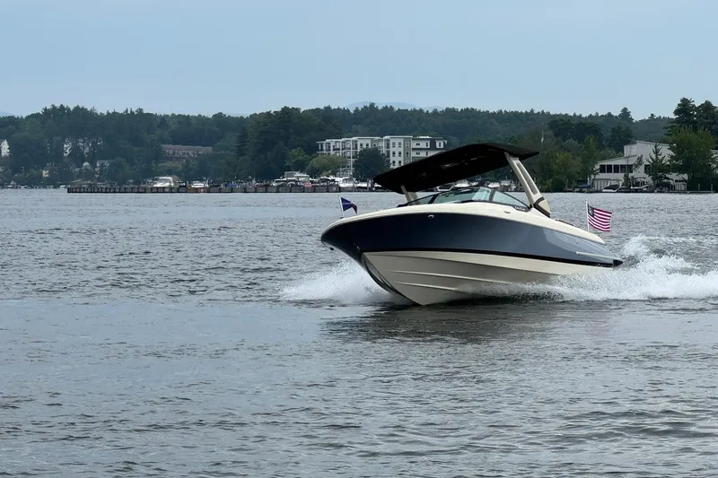 Slide: The Image of 2026 Chris-Craft Sportster 25 boat cruising on a lake with scenic shoreline backdrop. - 1