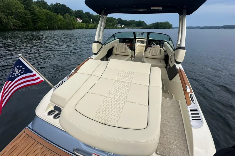 Slide: The Image of 2026 Chris-Craft Sportster 25 boat with luxurious seating, American flag, and scenic lake view. - 15
