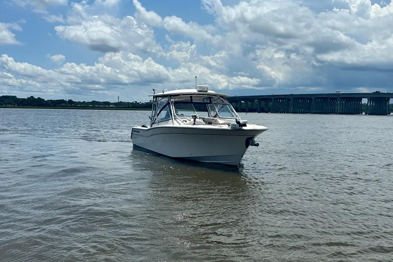 Slide: The Image of 2012 Grady-White Freedom 307 boat on water near a bridge under cloudy sky. - 2