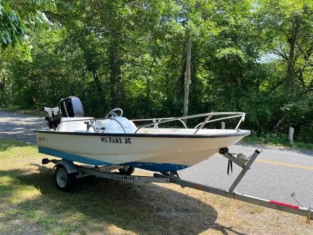 Slide: The Image of 2006 Boston Whaler 130 Sport boat on trailer, parked by a wooded roadside. - 10