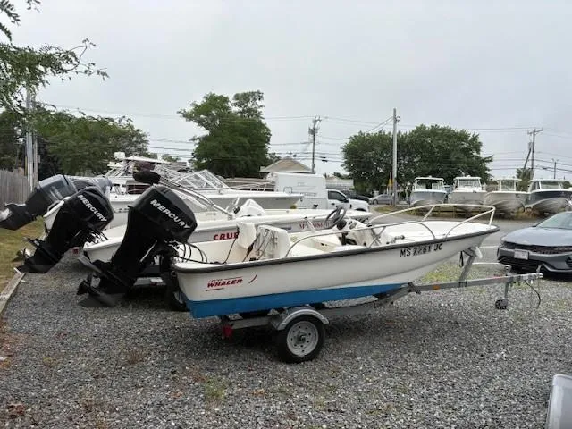 Slide: The Image of 2006 Boston Whaler 130 Sport boat on trailer, parked in a gravel lot. - 3