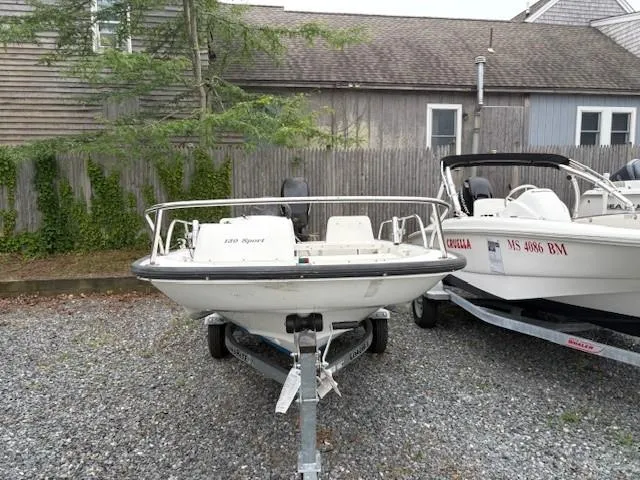 Slide: The Image of 2006 Boston Whaler 130 Sport boat on trailer, parked beside another boat. - 4