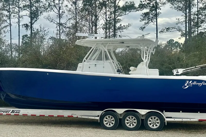Slide: The Image of 2013 Yellowfin 39 Offshore boat on trailer, parked near trees. - 1