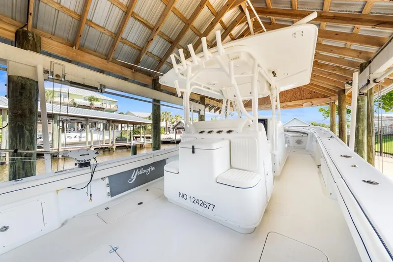 Slide: The Image of 2015 Yellowfin 39 boat docked under a wooden canopy, showcasing sleek design and spacious seating. - 22