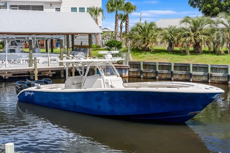 Slide: The Image of 2015 Yellowfin 39 boat on calm water, clear sky, and lush greenery in the background. - 3