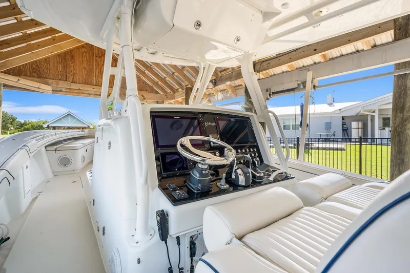 Slide: The Image of 2015 Yellowfin 39 boat interior with white seating and helm under a wooden dock shelter. - 34